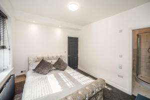 a white bedroom with a bed and a window at The Cosey Tucked-Away Cottage 2 or 3 bedrooms in Huddersfield