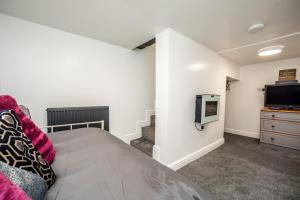 a bedroom with a bed and a tv on a wall at The Cosey Tucked-Away Cottage 2 or 3 bedrooms in Huddersfield