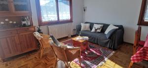 een woonkamer met een bank en een tafel en stoelen bij Appartamento con splendida vista su pista Stelvio in Bormio