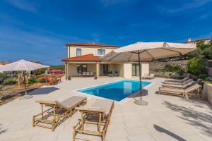 a pool with chairs and umbrellas and a house at Holiday house LUNA in Bajčići +38 photos