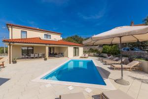a villa with a swimming pool and an umbrella at Holiday house LUNA in Bajčići