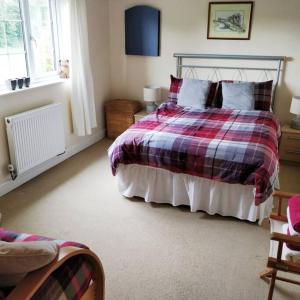 a bedroom with a bed with a plaid blanket at Large modern house in small rural Hamlet. in Duddon