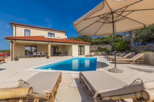 a villa with a swimming pool and an umbrella at Holiday house LUNA in Bajčići