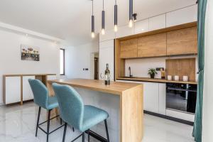 a kitchen with a wooden counter and blue chairs at Holiday house LUNA in Bajčići