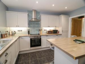 a kitchen with white cabinets and a sink at Big Azzles in Benllech