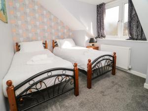 two twin beds in a room with a window at Big Azzles in Benllech