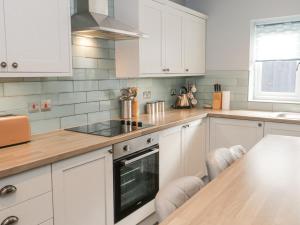 a kitchen with white cabinets and a wooden counter top at Hunters Cottage in Benllech