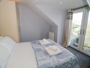 a bedroom with a bed with two towels on it at Hunters Cottage in Benllech