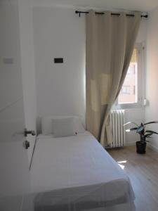 a white bed in a white room with a window at Apartamento grande en Huesca in Huesca