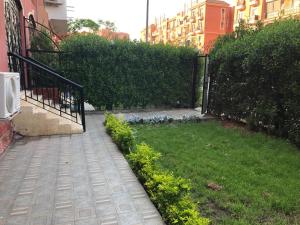a garden with a fence and a yard with grass at Cozy Apartmen with Garden in Sheikh Zayed in Sheikh Zayed