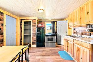 cocina con armarios de madera y nevera negra en Dog Friendly Private Cabin w Hot Tub Leadville-A, en Leadville