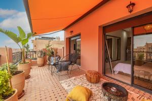 an orange house with a balcony with a table and chairs at L'Atlas - Appartement Authentique à Gueliz in Marrakesh