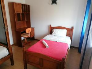 Un pequeño dormitorio con una cama con una manta roja. en Casa do Quebrado, en Peniche