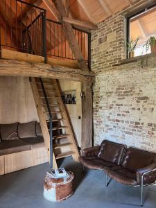 ein Wohnzimmer mit einem Sofa und einer Treppe in der Unterkunft Hoeve Appartement aan de rand van Maastricht met natuurzwembad in Berg en Terblijt