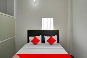 OYO Flagship Amazing Inn في Murādnagar: سرير مع وسائد حمراء وبيضاء في الغرفة