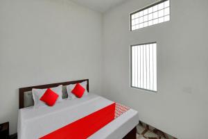 Murādnagar的住宿－OYO Flagship Amazing Inn，一间卧室配有一张带红色枕头的床和一扇窗户
