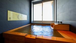 a bath tub with water in a room with a window at MURE Beppu in Beppu