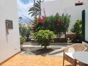 a patio with a table and chairs and a tree at Happy House Puerta del Sol in Caleta De Fuste
