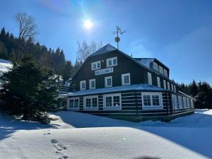 un gran edificio en la nieve con el sol detrás en Penzion Bílá Labuť, en Pec pod Sněžkou