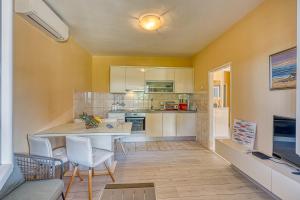 eine Küche mit gelben Wänden sowie einem Tisch und Stühlen in der Unterkunft Coastal Paradise Villa with Pool - Happy Rentals in Sveti Filip i Jakov