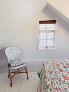 a bedroom with a bed and a chair next to a window at Cottage On Windsor in Cape Town