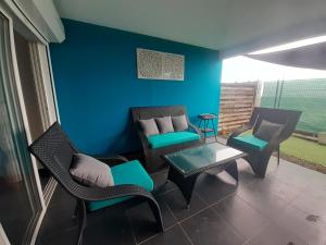 ein Wohnzimmer mit Stühlen, einem Sofa und einem Tisch in der Unterkunft Appartement spacieux moderne lumineux avec grand jardin dans résidence avec piscine in Le Gosier
