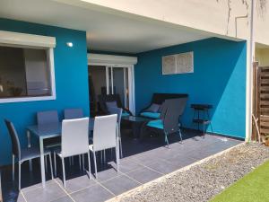 eine Terrasse mit Stühlen und einer blauen Wand in der Unterkunft Appartement spacieux moderne lumineux avec grand jardin dans résidence avec piscine in Le Gosier