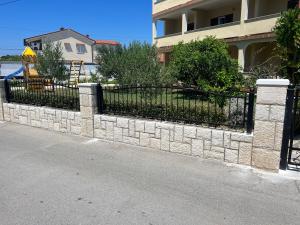 a stone retaining wall with a black gate at Apartments Pičuljan in Lopar