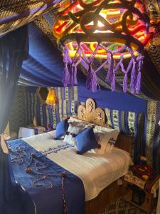 Tente et Restaurant ElBey في دوز: غرفة نوم مع سرير بسقف ملون