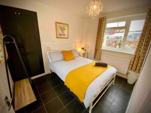 a bedroom with a bed with a yellow blanket on it at Brickworks - 2 bedrooms, 15 mins walk to the centre, with garden in Cardiff