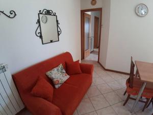 ein Wohnzimmer mit einem roten Sofa und einem Tisch in der Unterkunft Appartamento Sirena in Tortoreto Lido
