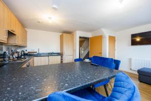 uma cozinha com um balcão preto e cadeiras azuis em Beautiful Large rooms in Ashford em Willesborough