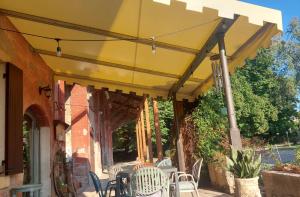 a yellow umbrella on a patio with chairs and tables at Ai Tigli in Castel dʼArio