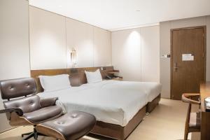 um quarto de hotel com uma cama e uma cadeira em 客村喆啡酒店（广州国际会议展览中心店） em Guangzhou