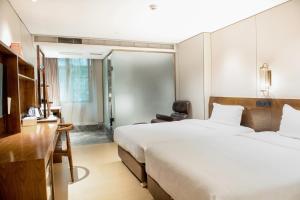 een hotelkamer met 2 bedden en een bureau bij 客村喆啡酒店（广州国际会议展览中心店） in Guangzhou