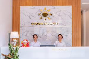 two women standing behind a counter with a computer at Golden Sun Hotel Hoi An in Hoi An