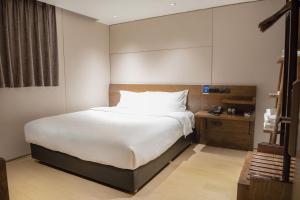 ein Schlafzimmer mit einem großen weißen Bett in einem Zimmer in der Unterkunft 客村喆啡酒店（广州国际会议展览中心店） in Guangzhou