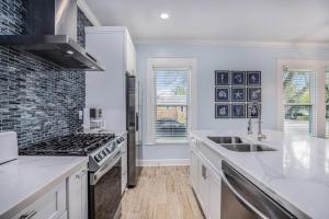 a white kitchen with a stove and a sink at Luxury Designer Villa by the Beach Bright Beautiful Brand New in Galveston