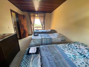 um quarto com três camas num quarto com uma janela em Casa Conchas do Mar na Barra de São Miguel