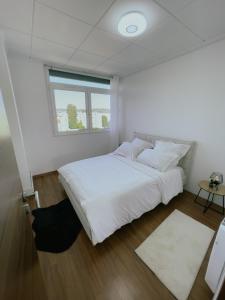 Un dormitorio con una gran cama blanca y una ventana en Appartement Cosy & Connecté à 15 min de Paris en Soisy-sous-Montmorency