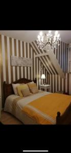 a bedroom with a bed with striped walls and a chandelier at L’hirondelle du Faubourg 