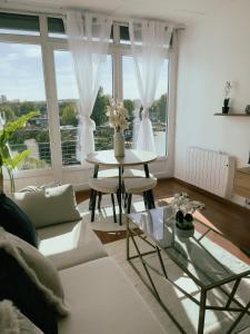 sala de estar con sofá blanco y mesa en Appartement Cosy & Connecté à 15 min de Paris en Soisy-sous-Montmorency