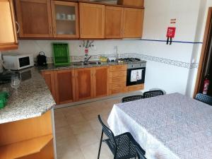 a kitchen with wooden cabinets and a table with chairs at Casa do Quebrado in Peniche