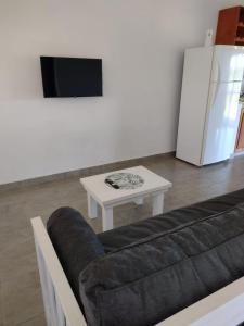 Una sala de estar con un sofá, una mesa y un refrigerador. en La casita de Isa, en Gualeguay