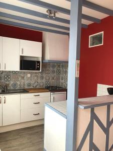 une cuisine avec des placards blancs et un mur rouge dans l'établissement Villa Liberté, à Villejuif