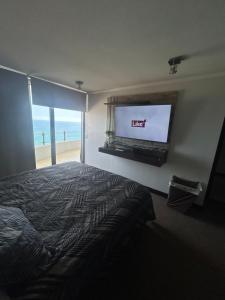 1 dormitorio con 1 cama y TV de pantalla plana en Departamento con hermosa terraza y vista panorámica al Mar 2D2B en Iquique