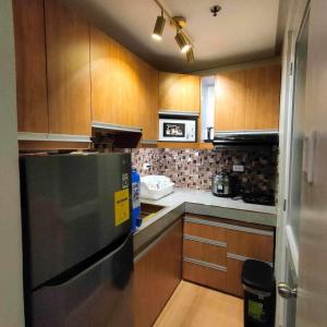 eine Küche mit Holzschränken und einem Kühlschrank aus Edelstahl in der Unterkunft Four Angels' 2 Bedroom in Manila