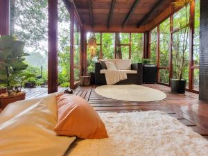 a screened in porch with a couch and chairs at Espaço Verde Novo Chalés in Teresópolis