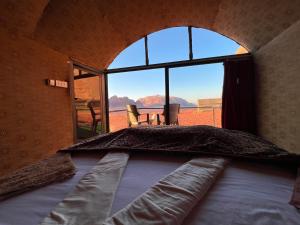 Bett in einem Zimmer mit einem großen Fenster in der Unterkunft Bedouin Lifestyle Camp in Wadi Rum