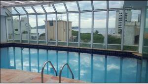 uma piscina com vista para um edifício em Apartamento Flat pé na areia com piscina aquecida no Guarujá